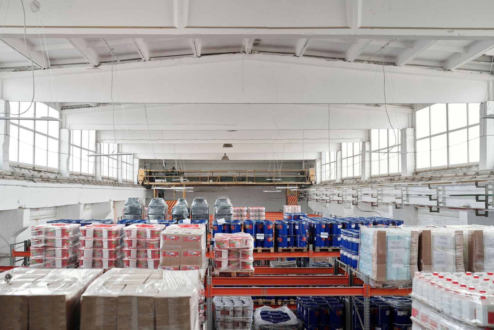 Galpón industrial con estanterías llenas de tambores, sacos y cajas sobre paletas